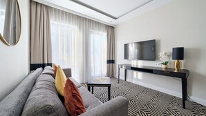 A modern living room with a sofa, a coffee table, a TV mounted on the wall, and a decorative lamp.