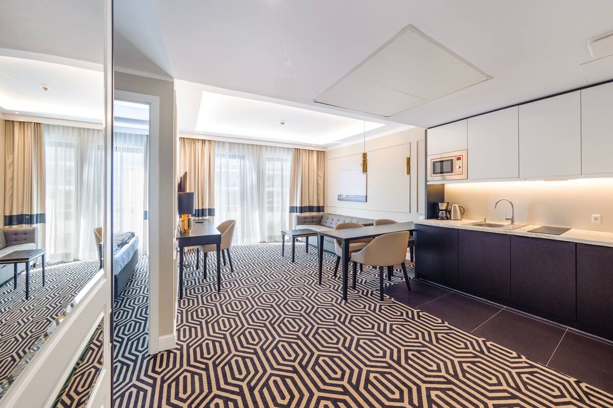 Een moderne hotelkamer met een zithoek, een keuken met een magnetron, en een vloer met een patroon.