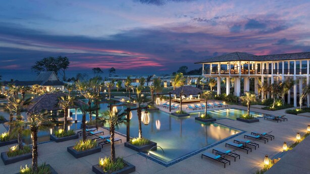 A resort pool area with multiple pools, lounge chairs, and palm trees.