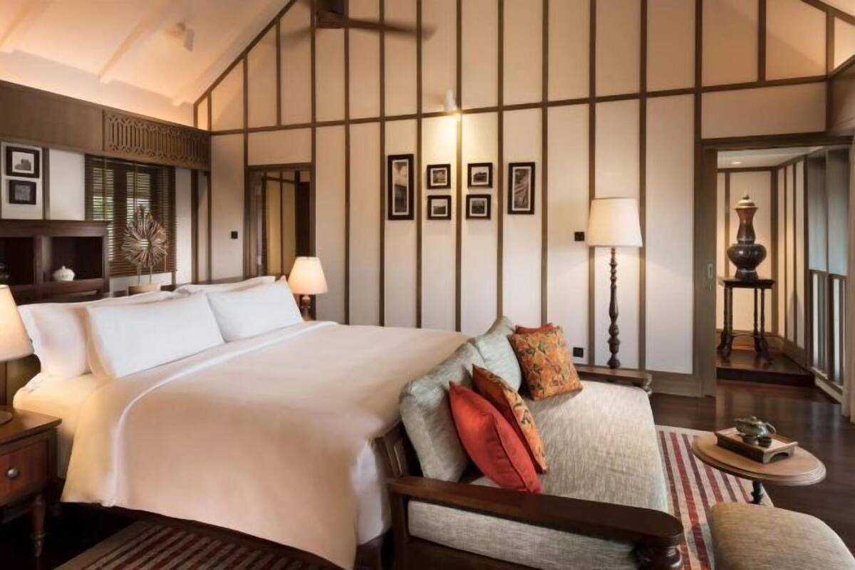A hotel room with a large bed, bedside tables, a lamp, a decorative wall panel, and framed pictures.