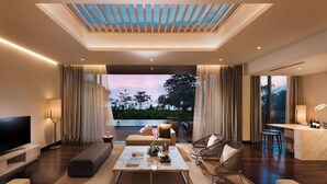Una sala de estar moderna con un televisor de pantalla plana grande, asientos cómodos, una mesa de centro y vistas al exterior.