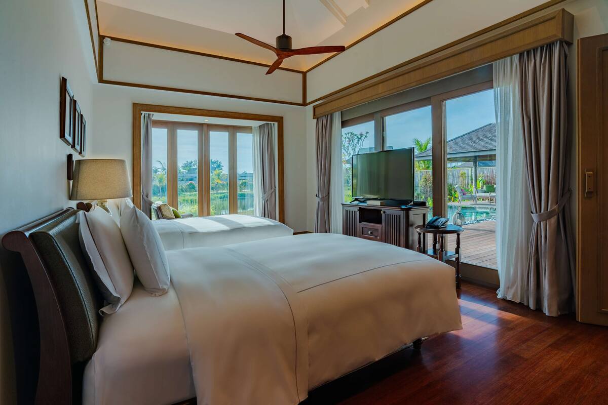 A spacious bedroom with a large bed, a ceiling fan, and a TV.
