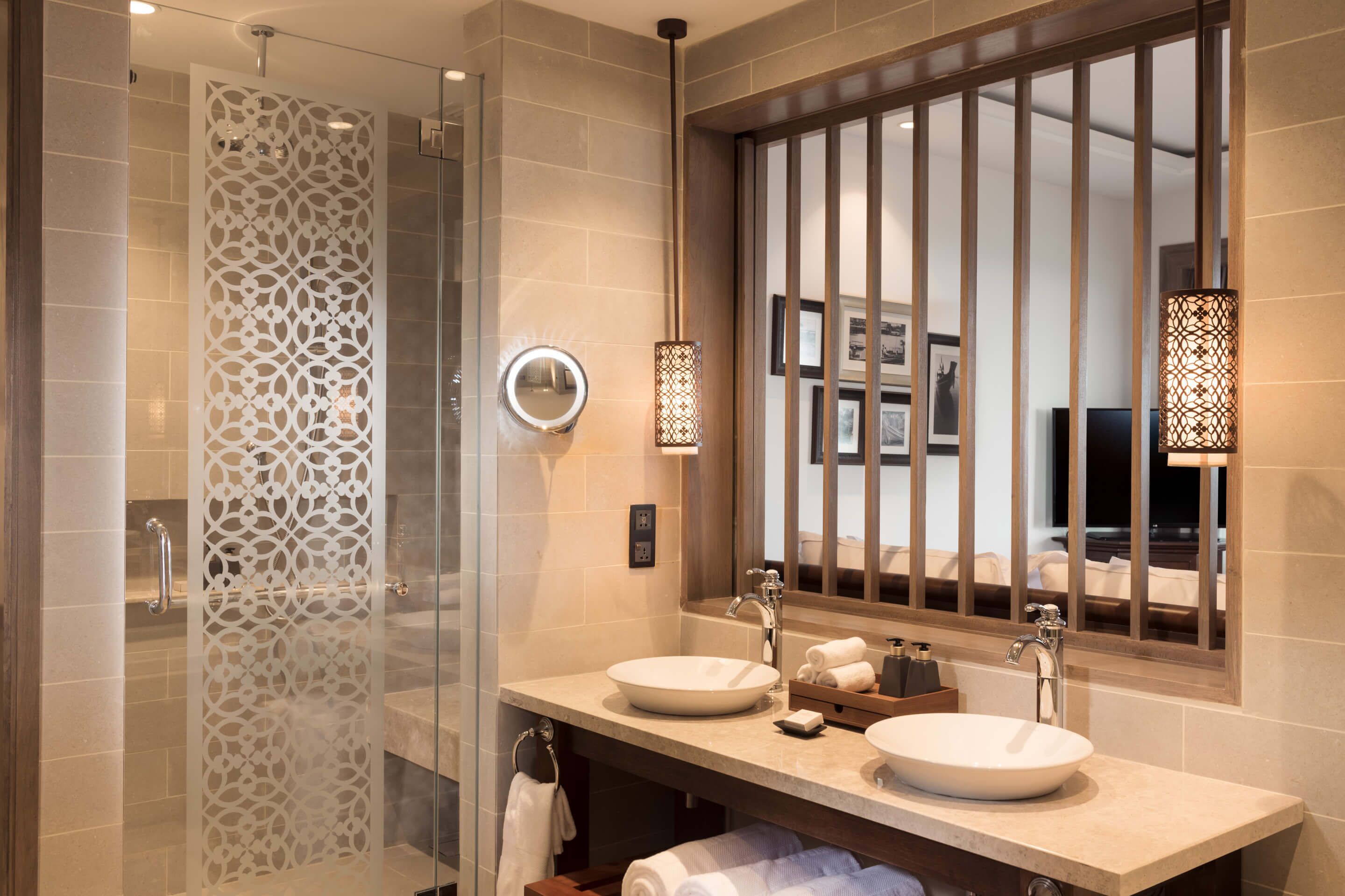 A modern bathroom with two sinks, a glass shower enclosure, and decorative lighting.