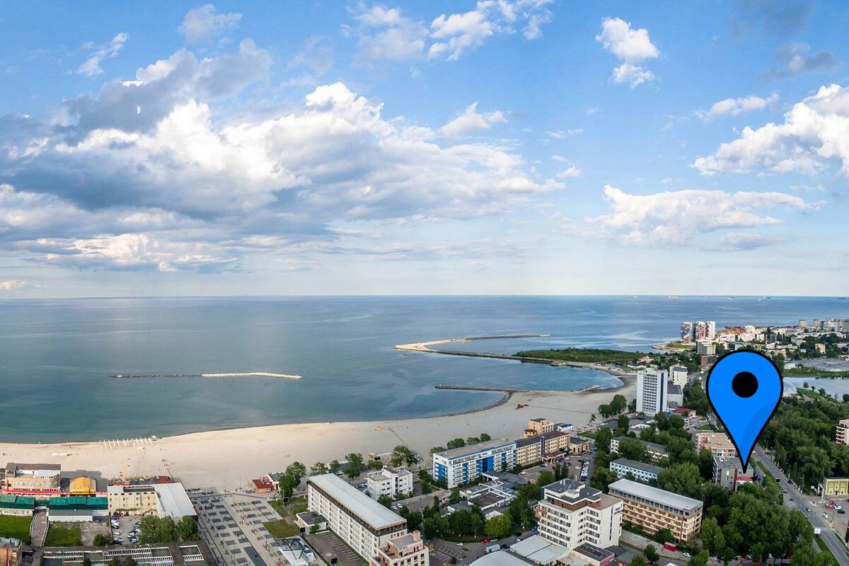 A coastal cityscape with a beach, buildings, and a clear sky.