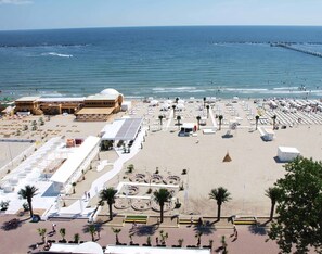 A beach with a large open area, a building with a dome, and a pier extending into the sea. - Apart holiday Coralia Mamaia CityLiving (Constanta)