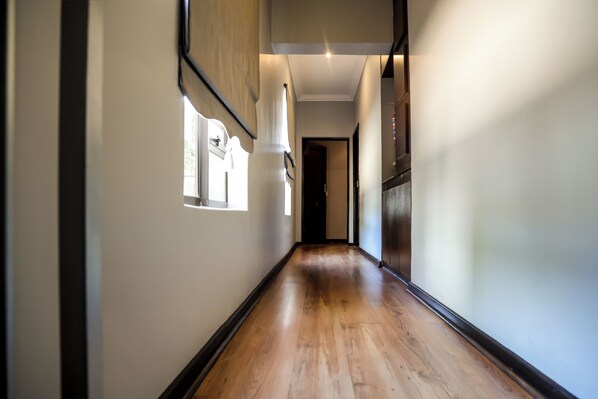 A long, narrow hallway with wooden flooring and white walls.