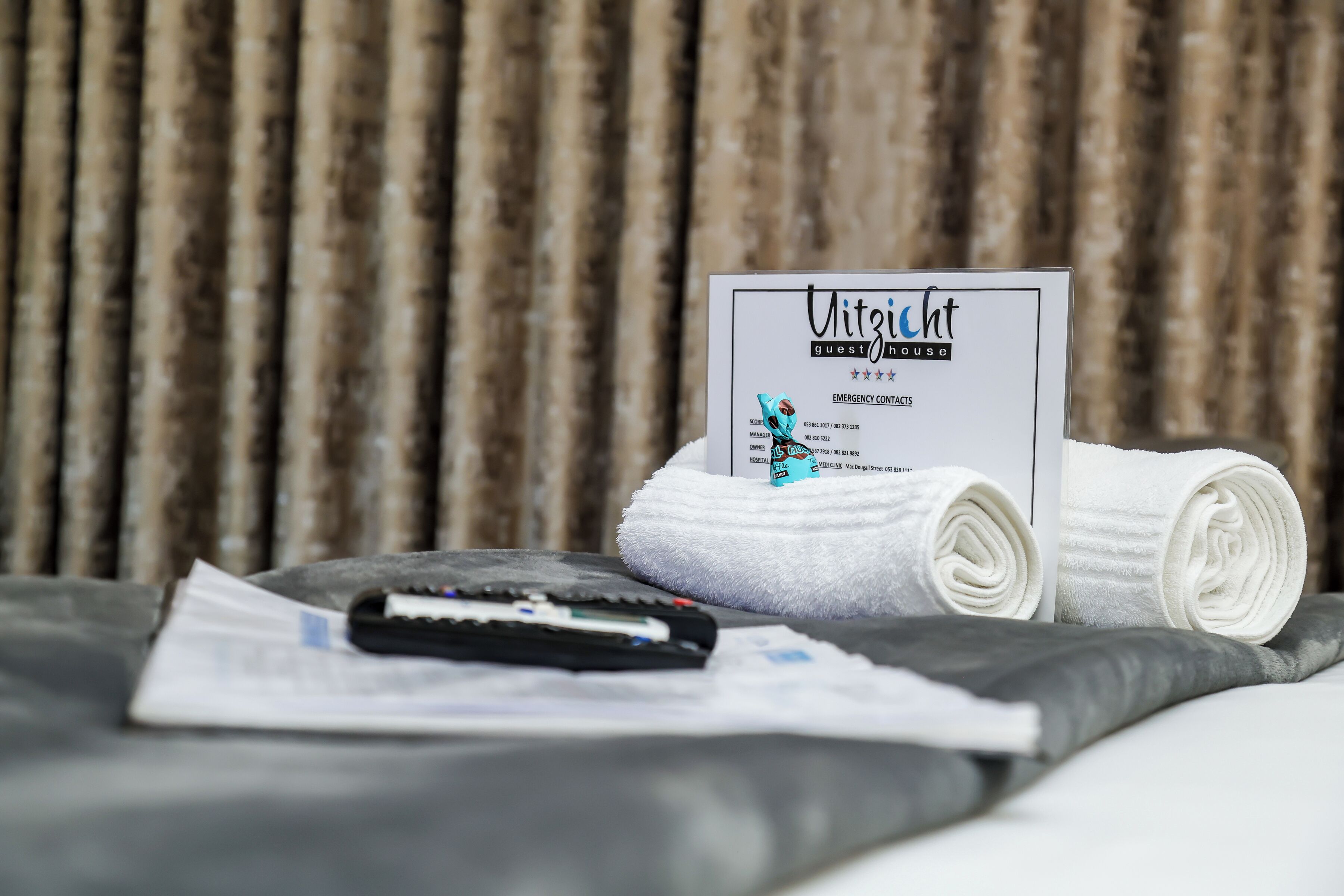 Une chambre d’hôtel avec un lit, une télécommande, une serviette pliée et une carte d’information pour les clients.