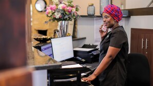 A reception desk with a computer, printer, and a vase of flowers. - Uitzicht Guest house (Kimberley)