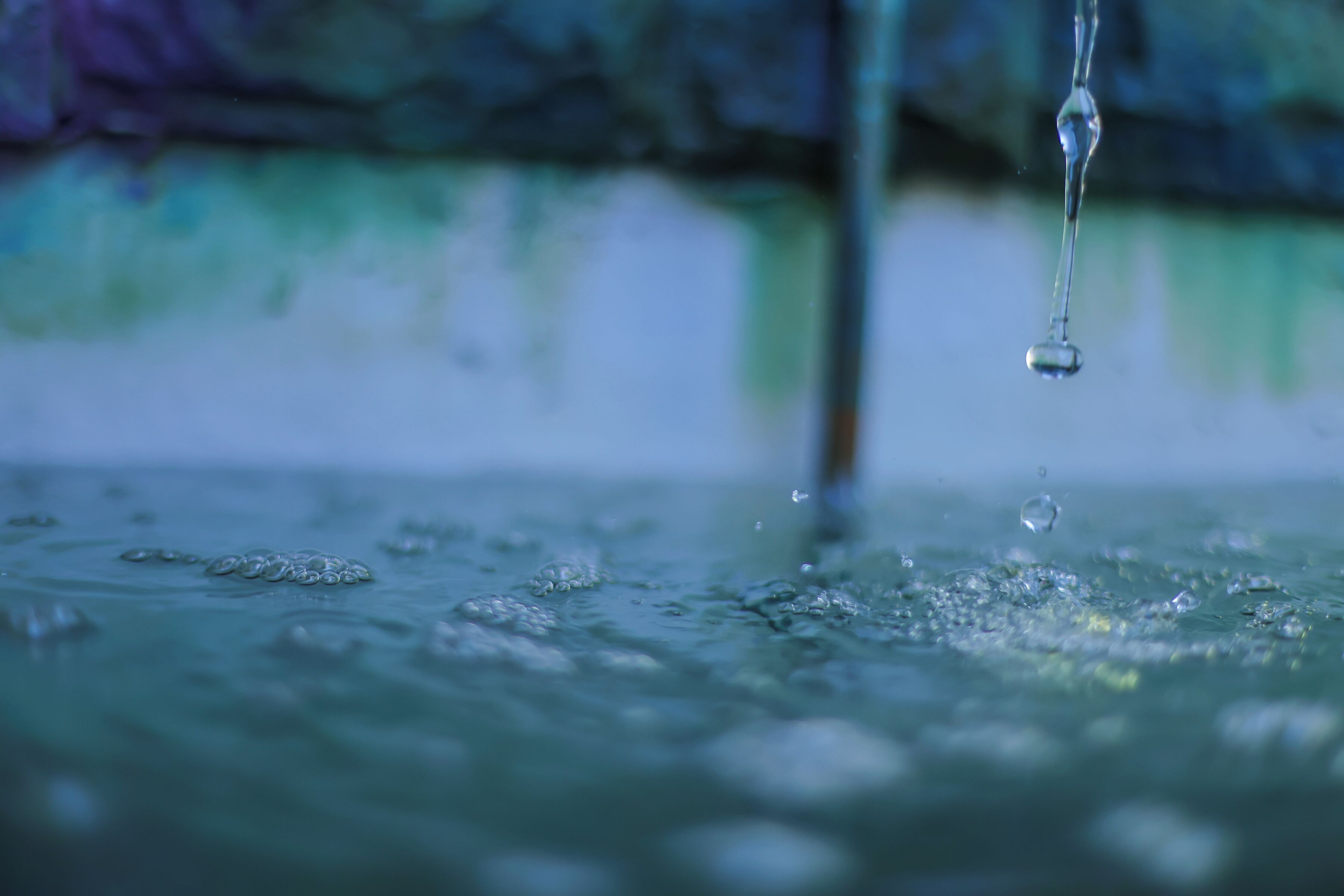 A close-up of a water droplet in motion, creating ripples on a surface.
