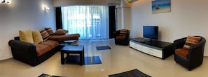 A modern living room with a sofa, coffee table, TV, and side chairs. - Apart holiday Maria Mamaia (Constanta)