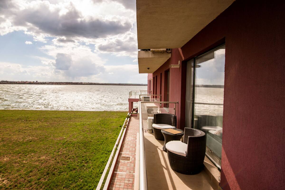 A balcony with wicker furniture overlooking a body of water.