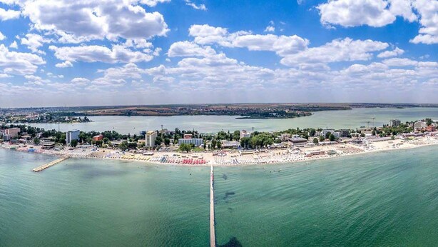An aerial view of a coastal city with a beach, buildings, and a clear sky. - Apart holiday Maria Mamaia (Constanta)
