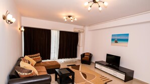 A modern living room with a sofa, coffee table, TV stand, and artwork on the wall. - Apart holiday Maria Mamaia (Constanta)