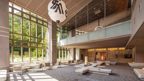 A spacious lobby with large windows, a high ceiling, and a seating area with sofas and chairs. - Kamenoi Hotel Arima (Kobe)