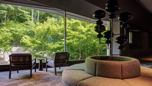 A modern living room with a large window, two chairs, a small table, and a unique spherical floor lamp. - Kamenoi Hotel Arima (Kobe)