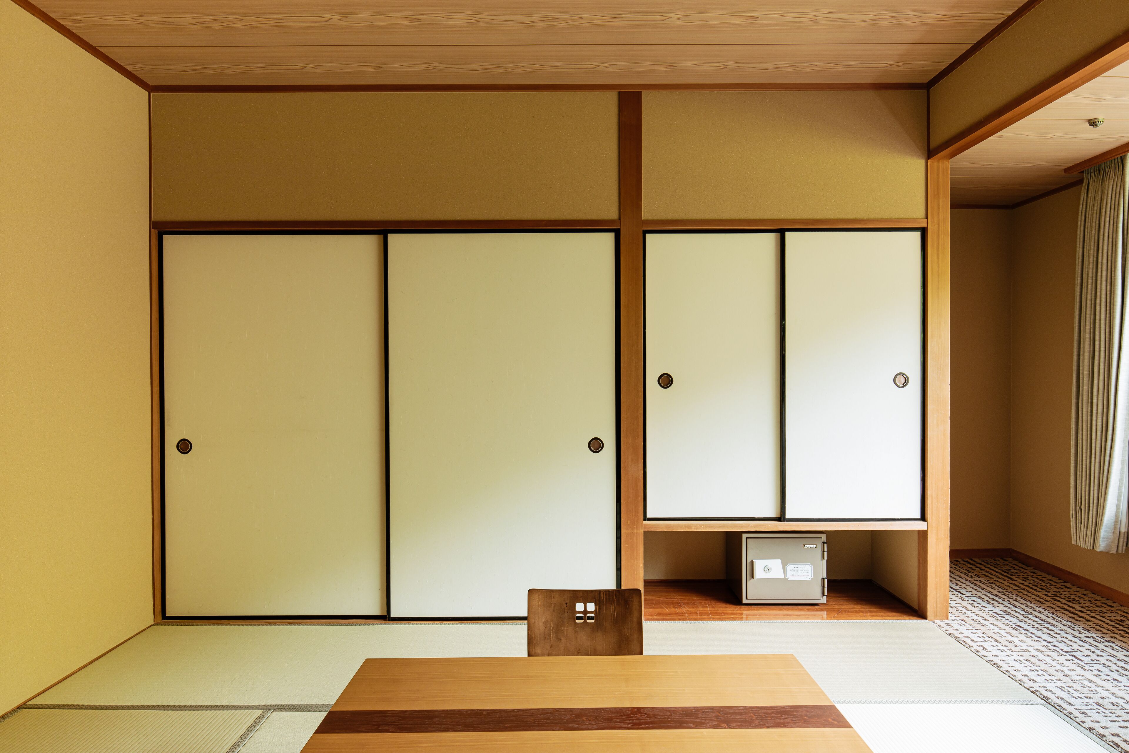 Um quarto japonês tradicional com tatames, portas deslizantes e uma mesa de madeira baixa.