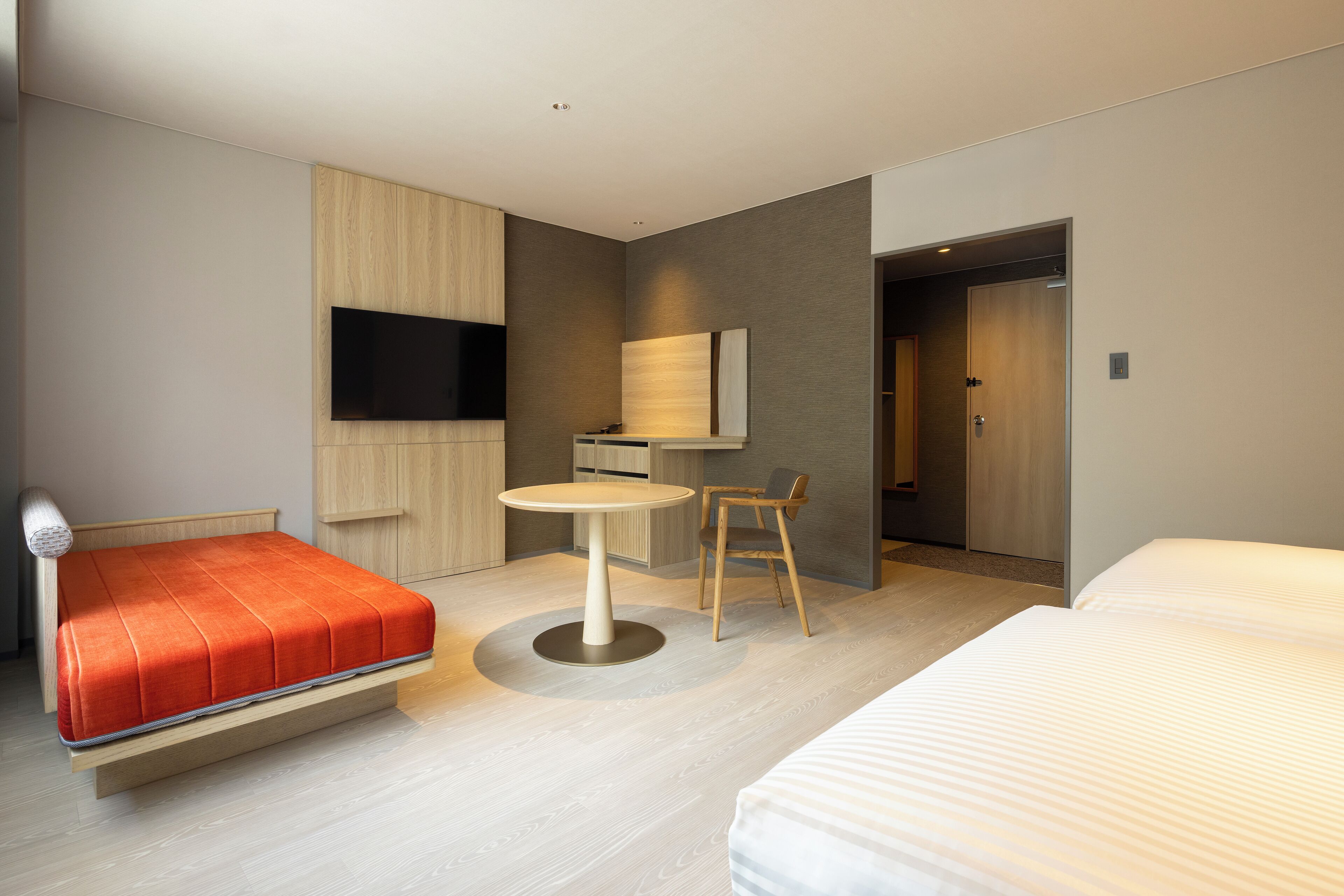 Una habitación de hotel moderna con cama, escritorio, silla, televisor y puerta.