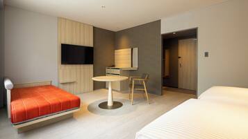 A modern hotel room with a bed, a desk, a chair, a TV, and a door.