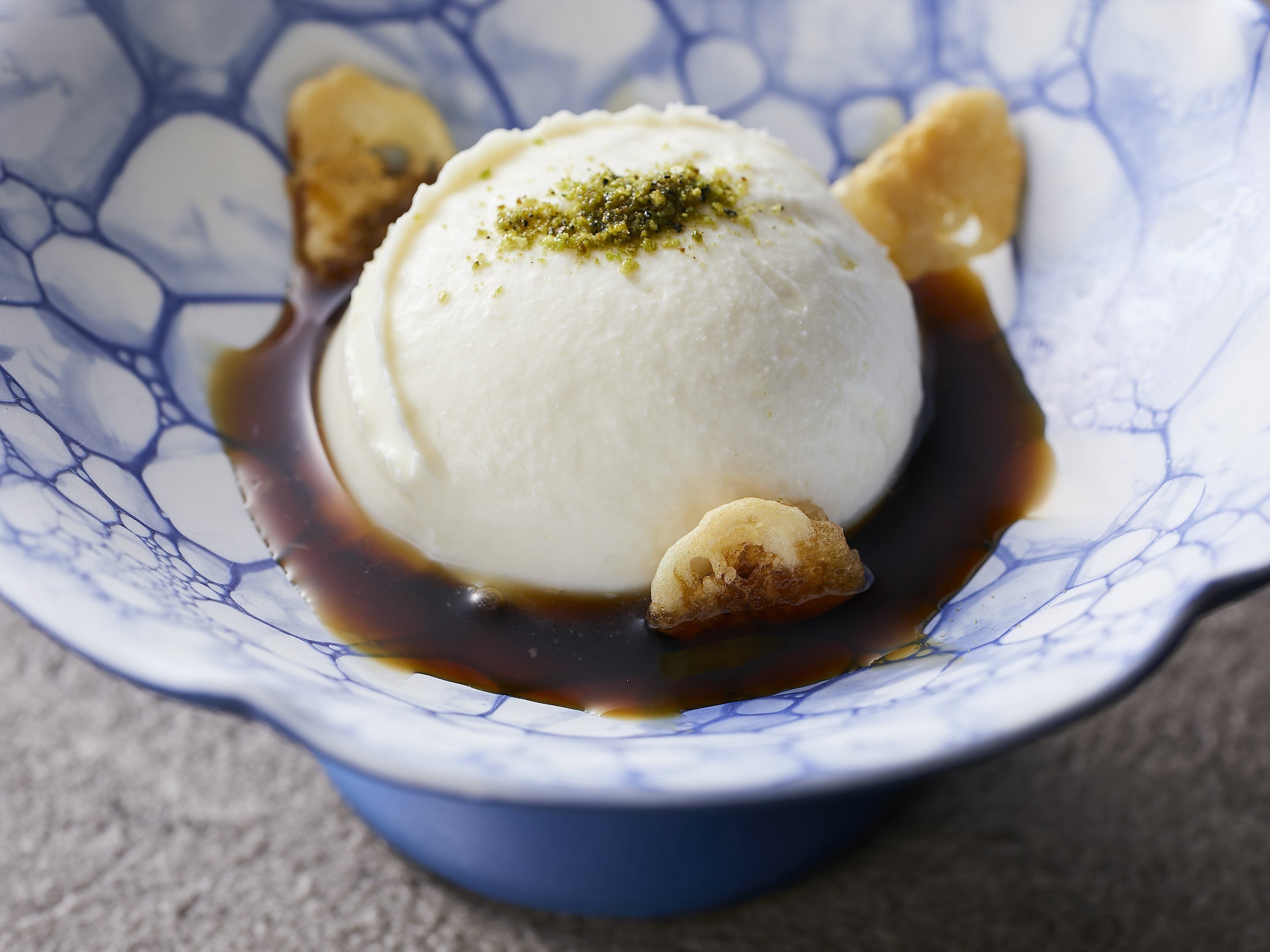 Dessert in een blauw geblueseerde kom met karamelsaus en noten.