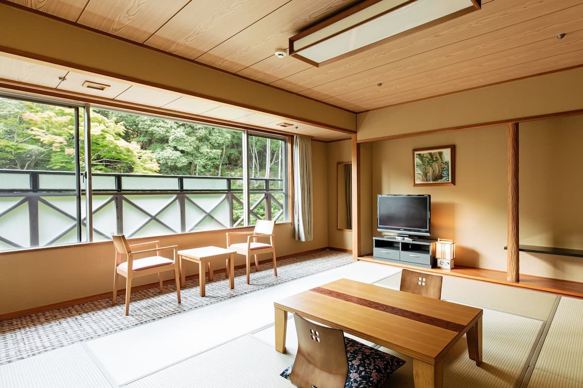 Una habitació japonesa tradicional amb tatami, televisió, taula i cadires.