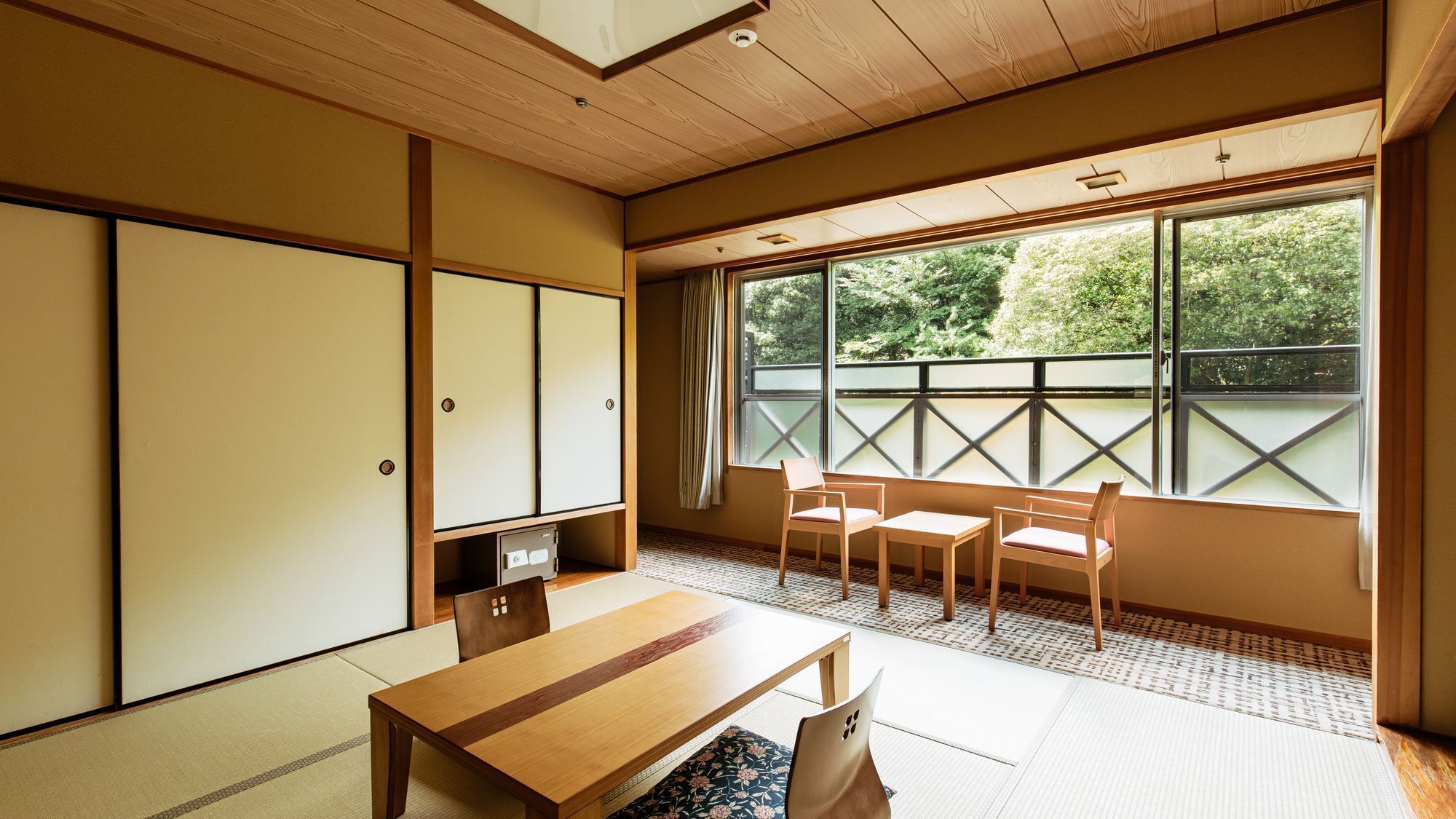 A traditional Japanese room with tatami flooring, a low table, chairs, and sliding doors.