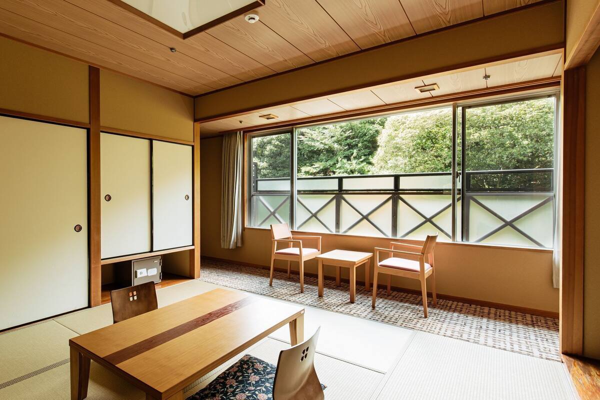 A traditional Japanese room with tatami flooring, a low table, chairs, and sliding doors.