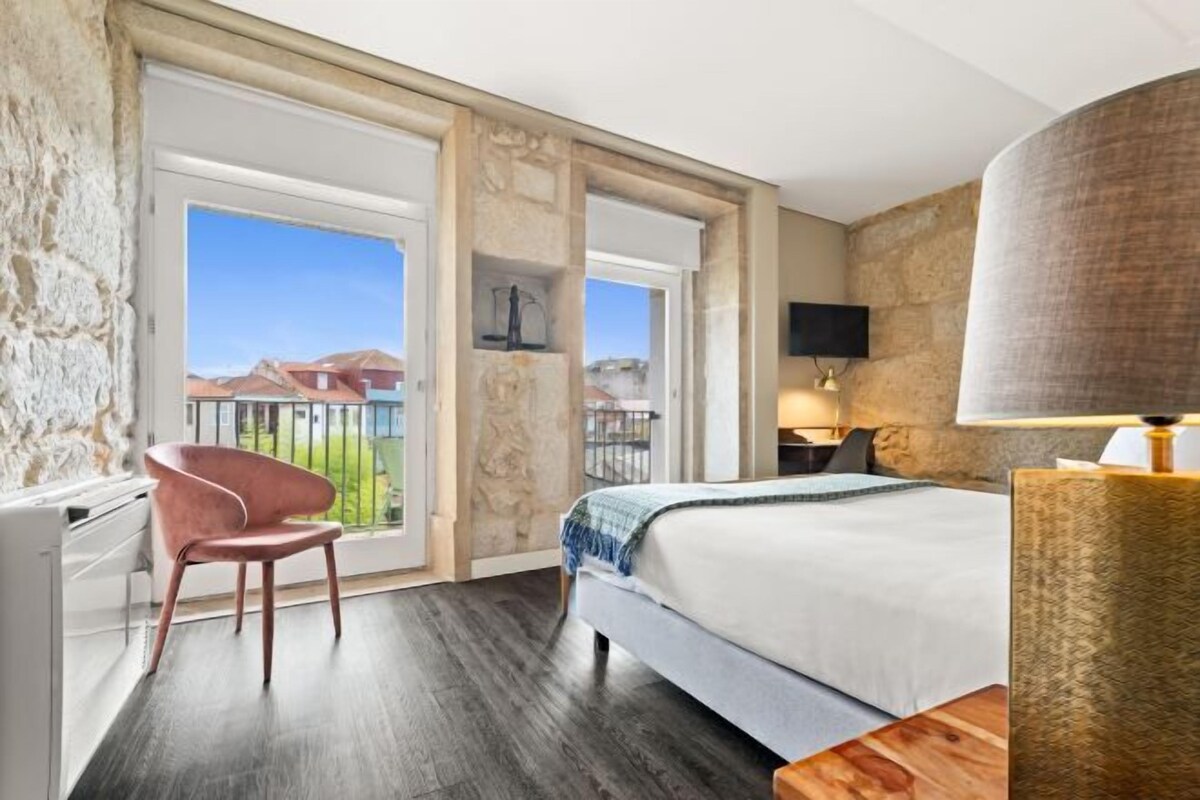 Een hotelkamer met een bed, een stoel, een bureau, een lamp en uitzicht.