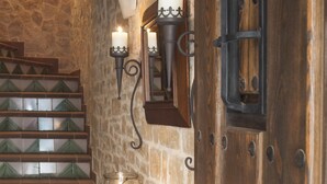 Eine Treppe mit grün gefliesten Stufen, ein Glas-Kerzenhalter mit einer brennenden Kerze und Wandleuchten.