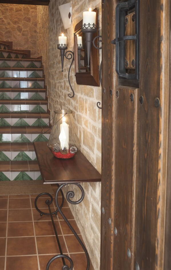 Una escalera con peldaños de baldosas verdes, un candelabro de cristal con una vela encendida y apliques de pared.