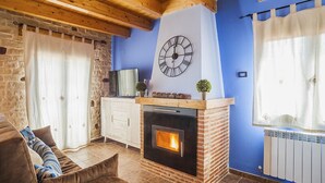 Ein gemütliches Wohnzimmer mit Kamin, einer Wanduhr und einer Steinwand.