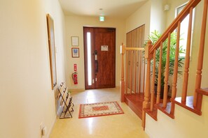 A hallway with a wooden staircase, a fire extinguisher, and a door with a sign. - D and Stay Resort (Okinawa)