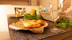 Une table à manger avec un panier de petits pains, un verre d’eau et un verre à vin.