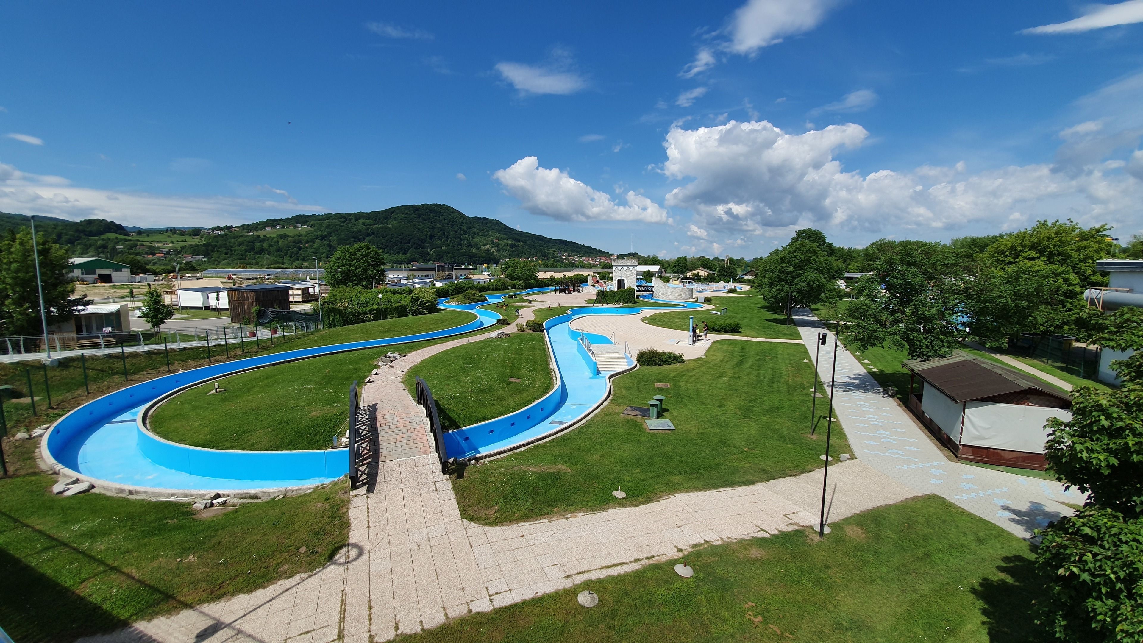 A water park with winding blue slides and a paved walkway.