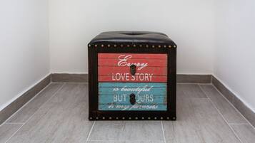 A small, square, wooden stool with a red, blue, and black color scheme and a sentimental message.