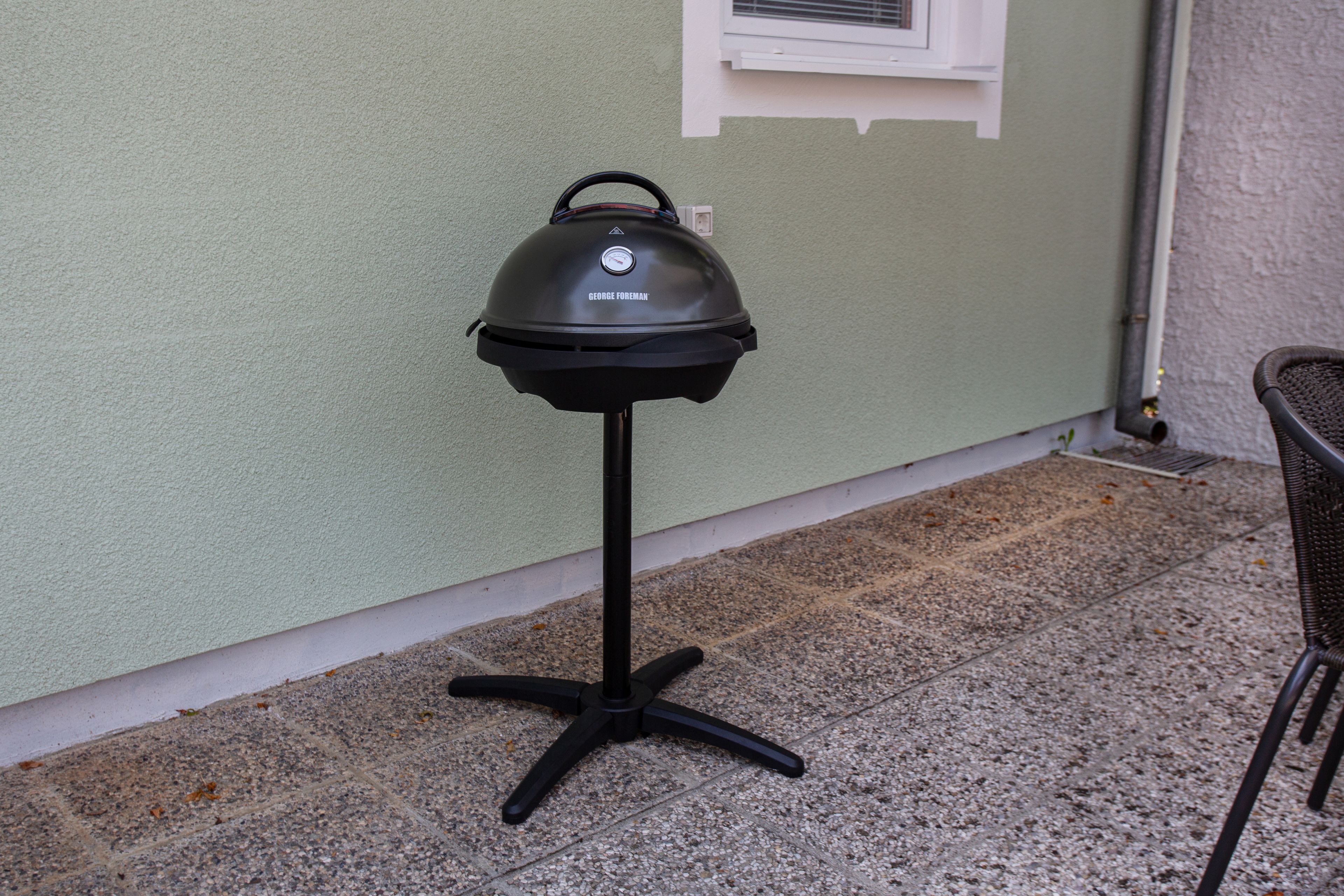 A portable grill on a tiled patio.