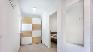 A hallway with a wooden and white partition, a bed with a mattress and pillows, and a large mirror on the wall. - Holiday house in Terme Catez (Brezice)