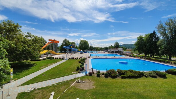 A large outdoor swimming pool with adjacent water slides, surrounded by well-maintained grass and trees. - Holiday house in Terme Catez (Brezice)