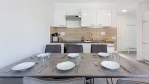 A modern dining area with a grey table set for six, white plates, and cutlery. - Holiday house in Terme Catez (Brezice)