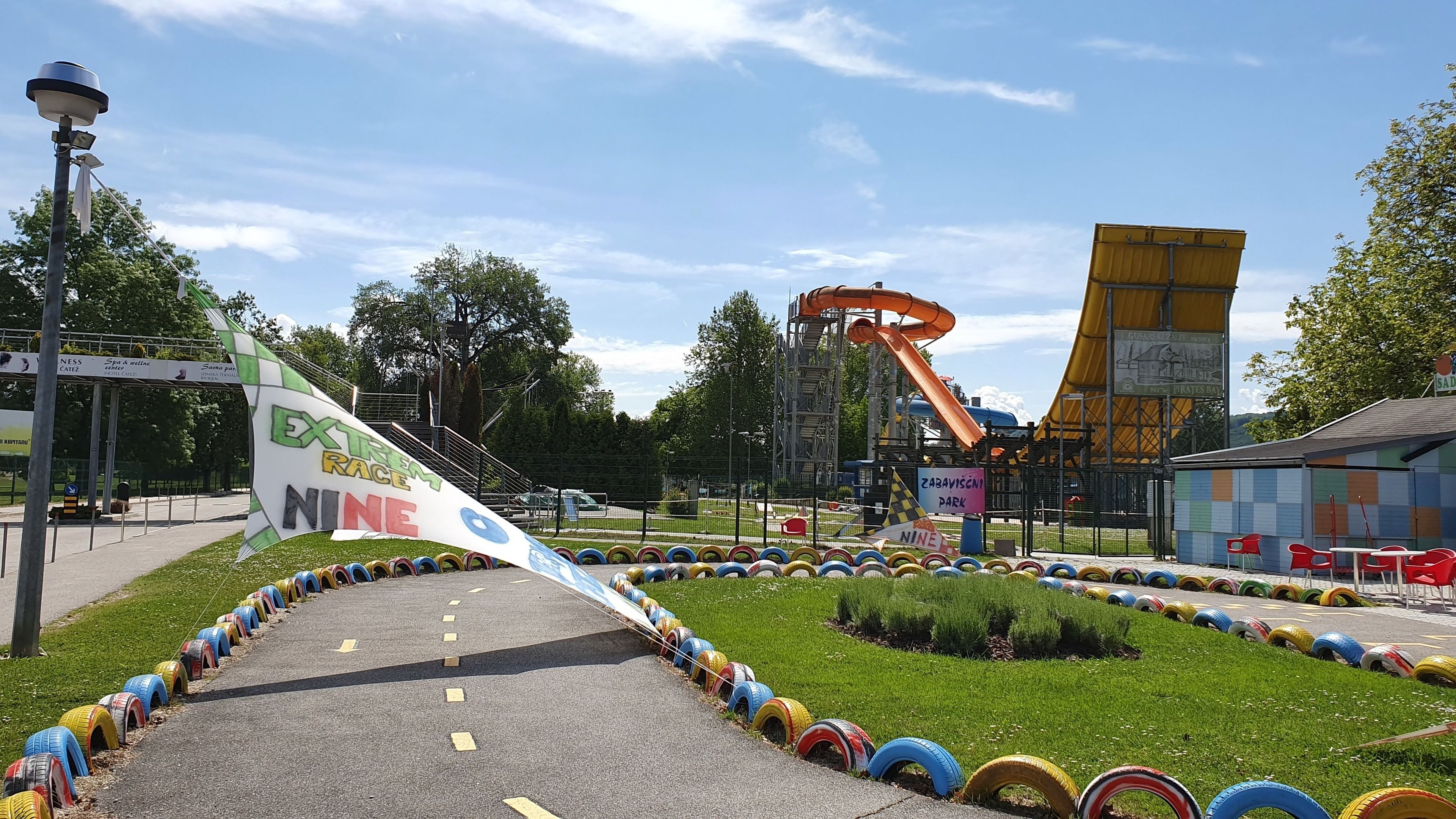 A park with a tire track path, a flag, and a water slide.