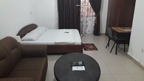 A hotel room with a bed, a sofa, a small table, and a desk. - Restall Guest Lodge (Adentan)