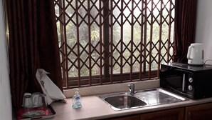 A kitchen with a window, a sink, a microwave, and a coffee maker. - Restall Guest Lodge (Adentan)