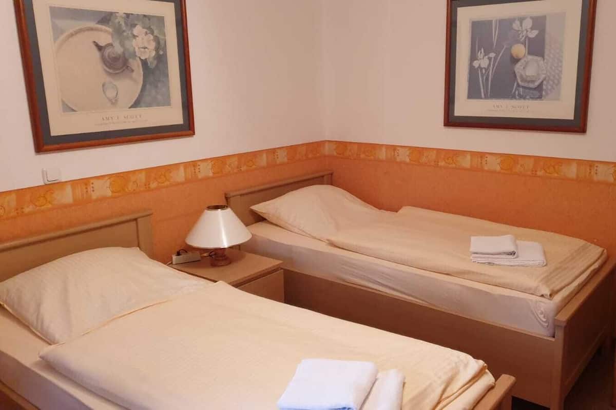 Quarto com duas camas de solteiro, mesa de cabeceira com luminária e uma cadeira.
