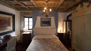 Een slaapkamer met een groot bed, een kroonluchter, een schilderij aan de muur en een kledingkast.