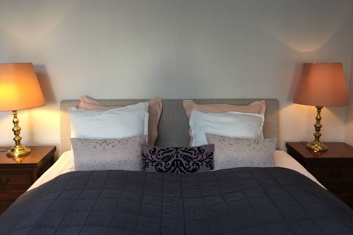 A bed with a dark quilt, two nightstands with lamps, and patterned pillows.