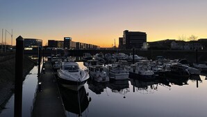 A marina with boats docked, a waterway, and buildings in the background. - Rhein Yacht Lexa (Duisburg)