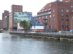 A riverside view with a bridge, buildings, and a small boat docked near the water.