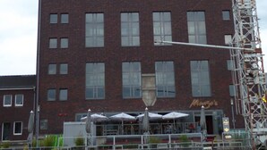 A multi-story brick building with a flat roof, large windows, and a sign reading "Monzo's". - Rhein Yacht Lexa (Duisburg)