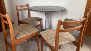 Mesa redonda con cuatro sillas de madera con asientos de mimbre.