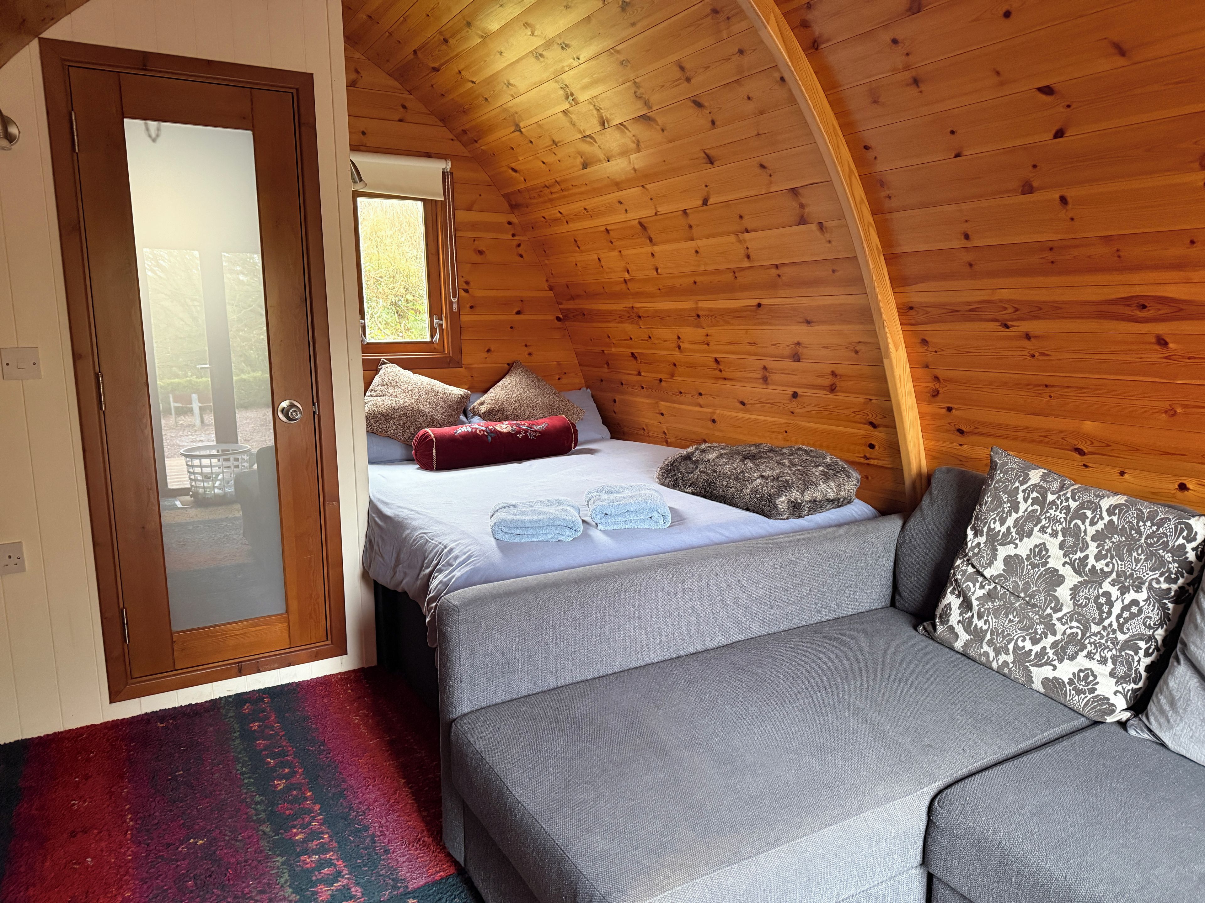 Een gezellige kamer met een bed, een bank en een raam.