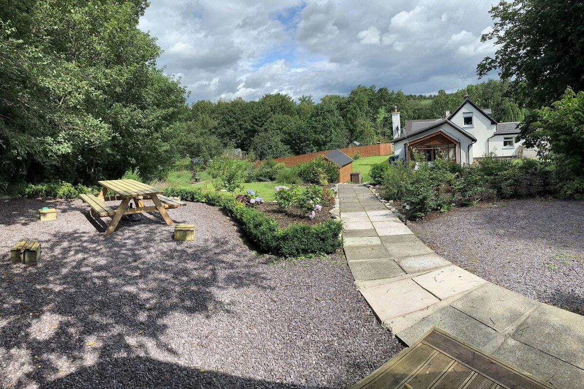 A garden with a picnic table and a gravel path leading to a house.